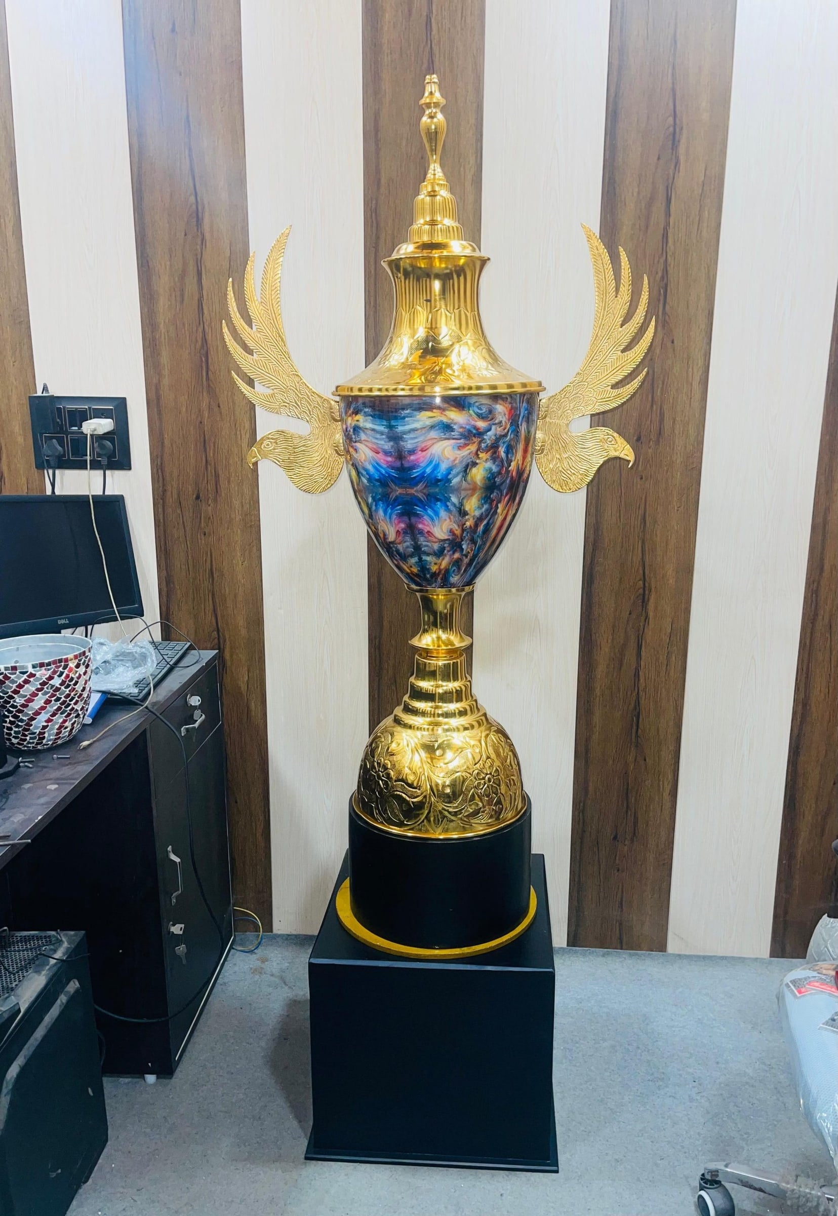 Falcon Cup with a blue, purple and gold marbled bowl between gold falcon wings, on a black plinth